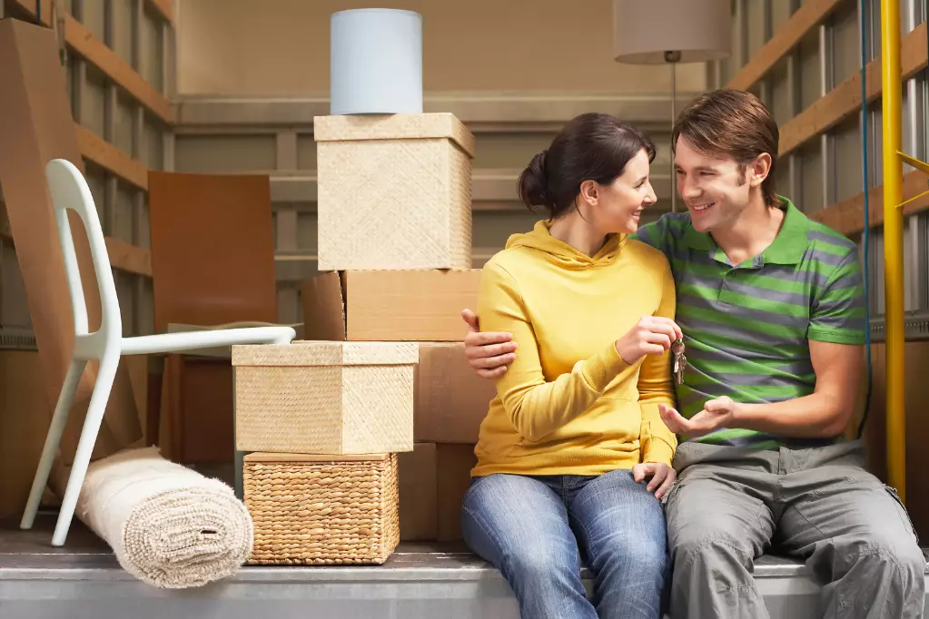 Couple Sitting in Back of Moving Van handing over keys